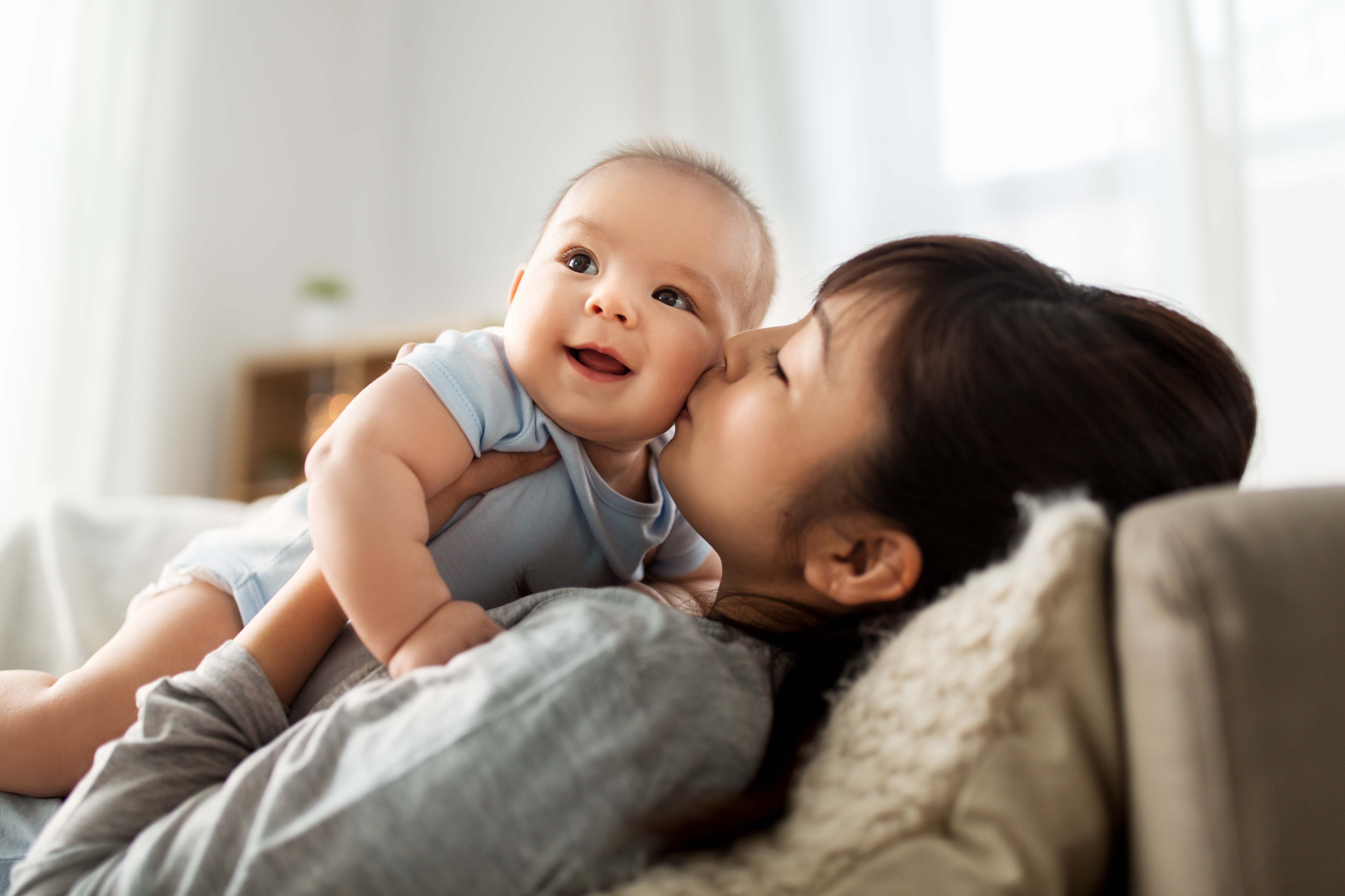 happy mother kissing little baby son at home